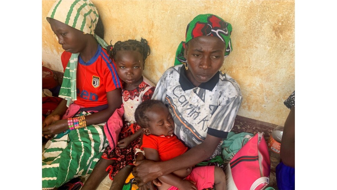 FILE - A woman who fled the violent rebellion in Central African Republic (CAR) sits with her family as they await their registration process, in the border town of Garoua-Boulai, Cameroon, Jan. 7, 2021.