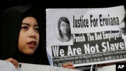 A supporter of Indonesian maid Erwiana Sulistyaningsih, holds a placard as Sulistyaningsih arrives at a court in Hong Kong, Feb. 10, 2015.