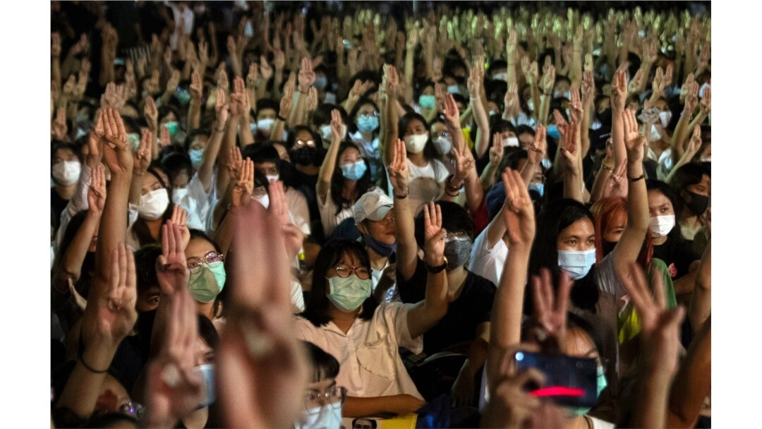FILE - Pro-democracy students raise a three-finger salute, a resistance symbol borrowed by Thailand's anti-coup movement from the movie "The Hunger Games," during a protest at Thammasat University near Bangkok, Thailand, Aug, 10, 2020.