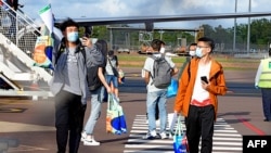 Mahasiswa asing turun dari penerbangan internasional di Bandara Darwin di Australia, 30 November 2020. (Foto: JULES / Charles Darwin University / AFP)