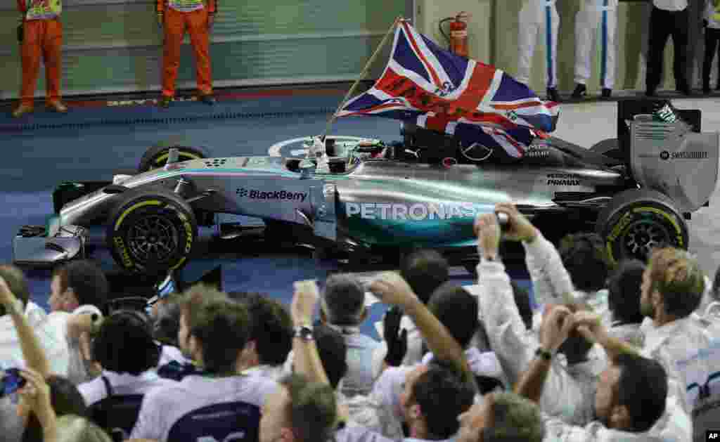 Pembalap Mercedes Lewis Hamilton dari Inggris membawa bendera Inggris setelah memenangkan Abu Dhab Formula one di jalur balap Yas Marina di Abu Dhabi, Uni Emirat Arab.