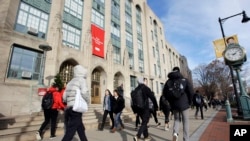 FILE - In this Nov. 29, 2018, photo students and passers-by walk past an entrance to Boston University College of Arts and Sciences in Boston. 