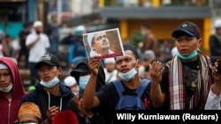 Seorang demonstran mengacungkan gambar Rizieq Shihab yang baru saja divonis karena melanggar pembatasan terkait COVID-19, Kamis, 24 Juni 2021. (Foto: Willy Kurniawan/Reuters)