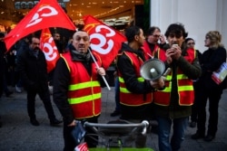 Members of the French national trade union General Confederation of Labour (CGT) distribute leaflets during a rally by the department store Au Printemps, in central Paris, Jan. 3, 2020.