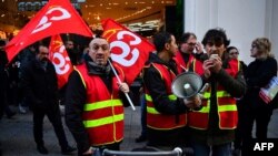 Members of the French national trade union General Confederation of Labour (CGT) distribute leaflets during a rally by the department store Au Printemps, in central Paris, Jan. 3, 2020.