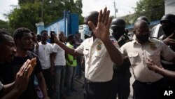 People pressure police to hand over two men who were arrested and the bodies of two men killed by police, in order to burn them in retaliation for the assassination of the President, Port-au-Prince, July 8, 2021.