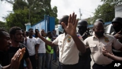 People pressure police to hand over two men who were arrested and the bodies of two men killed by police, in order to burn them in retaliation for the assassination of the President, Port-au-Prince, July 8, 2021.