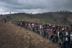 FILE - Displaced persons gather during a visit by the Congolese defense minister, not pictured, to the internally displaced persons camp of Bijombo, South Kivu Province, eastern Democratic Republic of Congo, Oct. 10, 2020.