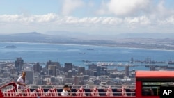 FILE—An open-air double decker sightseeing bus stops on the slopes of Table Mountain, overlooking the city of Cape Town, South Africa, March, 20, 2020.