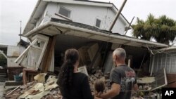 Maree, left, daughter Jasmine, center, and Norm Butcher take a look at their destroyed home in Christchurch, New Zealand , February 26, 2011