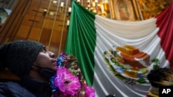 ARCHIVO: Un peregrino mira la imagen de Nuestra Señora de Guadalupe dentro de la Basílica de Guadalupe en su día festivo en la Ciudad de México, la madrugada del martes 12 de diciembre de 2023.