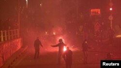 Flares burn near protesters, as they clash with police officers during a demonstration against a police crackdown on gatherings, in Athens, Greece, March 9, 2021.