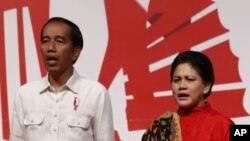 Presiden Joko Widodo dan ibu negara, Iriana, menyanyikan lagu "Indonesia Raya" dalam pertemuan dengan warga Indonesia di Hong Kong, 30 April 2017. (AP Photo/Vincent Yu)