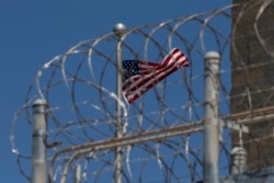 FILE - A US flag flies inside the razor wire of the Camp VI detention facility in Guantanamo Bay Naval Base, Cuba, in April 2019.