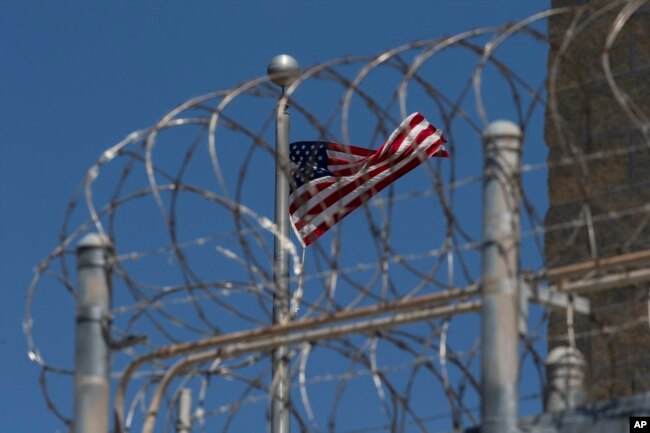 FILE - In this April 17, 2019 file photo reviewed by U.S. military officials, a U.S. flag flies inside the razor wire of the Camp VI detention facility in Guantanamo Bay Naval Base, Cuba.