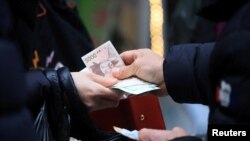 한국 서울의 전통시장에서 한 여성이 현금으로 물건을 계산하고 있다. (자료화면)