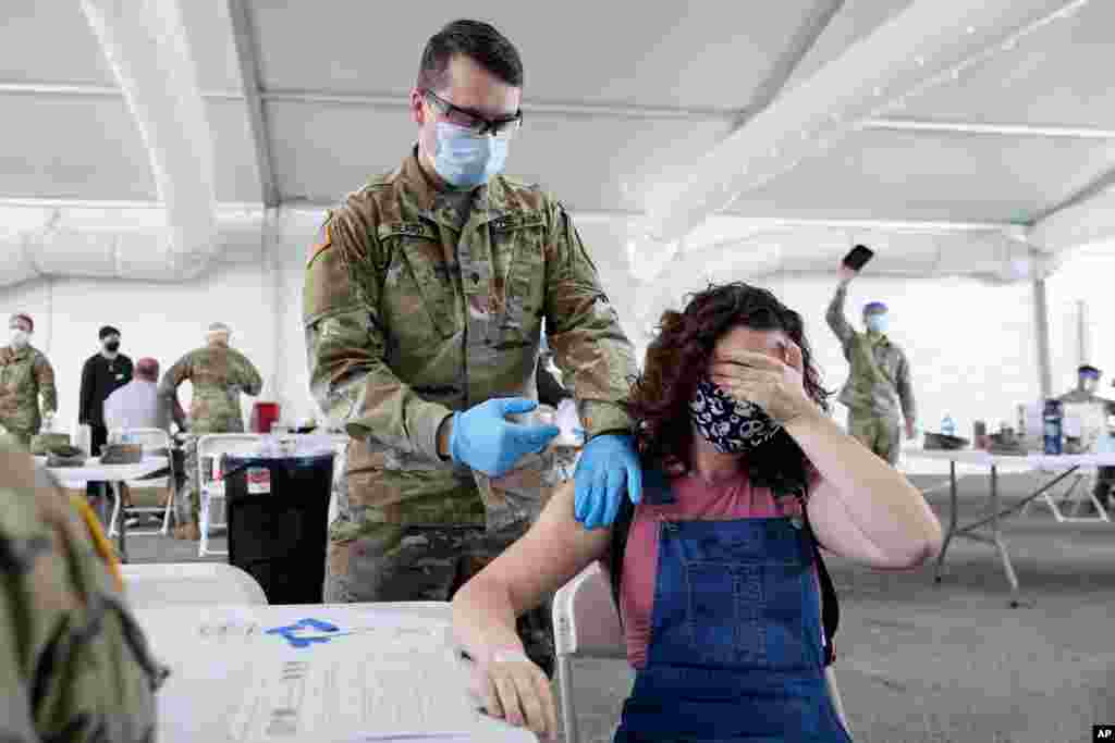 Leanne Montenegro covers her eyes while she receives the Pfizer COVID-19 vaccine at a FEMA vaccination center at Miami Dade College, in Miami, Florida, April 5, 2021.