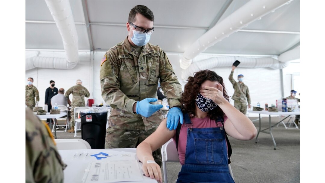 FILE - Leanne Montenegro covers her eyes while she receives the Pfizer COVID-19 vaccine at a FEMA vaccination center at Miami Dade College, in Miami, Florida, April 5, 2021.