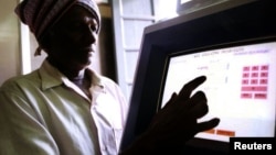 FILE - An Indian farmer uses a computer to check land-records in the village of Ramanagaram 40 km (25 miles) in the southern Indian state of Karnataka, May 26, 2001. 