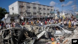 People walk amidst destruction at the scene of a double car bombing at a busy intersection, a day after the attack, in Mogadishu, Somalia, Oct. 30, 2022.