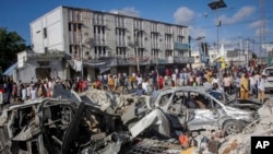 FILE - People walk by scene of a double-car bombing a day after the attack in Mogadishu, Somalia, Oct. 30, 2022. Violence continued this week, as Somali police say at least two people were killed by an explosion that hit a vehicle carrying students in Mogadishu on Thursday.