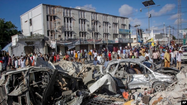 FILE - People walk amidst destruction at the scene of a double car bombing at a busy intersection, a day after the attack that killed 121 people in Mogadishu, Somalia, Oct. 30, 2022. The attack targeted the country's Ministry of Education.