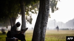 FILE - A man reads a newspaper while sitting on a bench at a park in New Delhi on Nov. 18, 2020. Media group Report for the World helps support newsrooms around the globe by training and supporting journalists in underrepresented communities. (Jewel Samad/AFP)