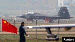 A China-made J-31 stealth fighter (background) lands on a runway after a flying performance at the China International Aviation and Aerospace Exhibition in Zhuhai, Guangdong province, Nov. 11, 2014.