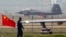 A China-made J-31 stealth fighter (background) lands on a runway after a flying performance at the China International Aviation and Aerospace Exhibition in Zhuhai, Guangdong province, Nov. 11, 2014.