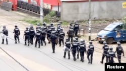 FILE - A still image taken from video shows riot police walk along a street in the English-speaking city of Buea, Cameroon Oct. 1, 2017.