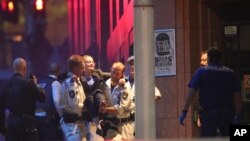 An injured hostage is carried to an ambulance after gunfire erupted during a cafe siege in the central business district of Sydney, Australia, Dec. 16, 2014.