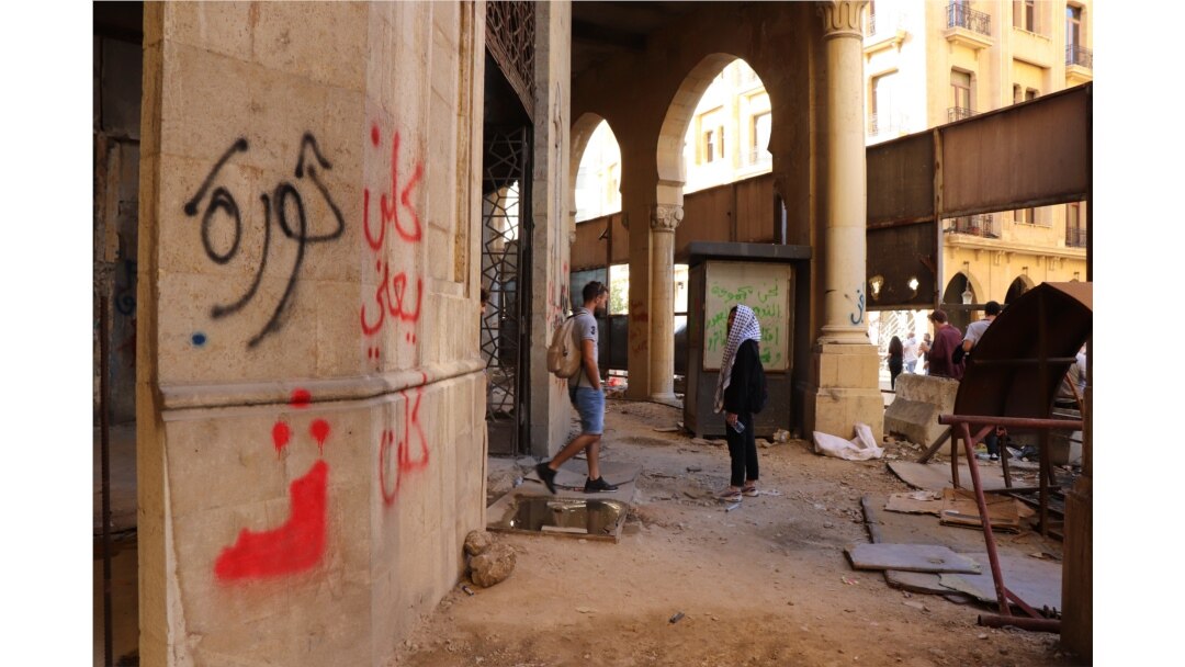 Many of the boards closing up this abandoned building have been torn down and graffiti, including writing that says "revolution" and "all of them means all of them," now covers the walls, in Beirut, Nov. 19, 2019. (Heather Murdock/VOA)