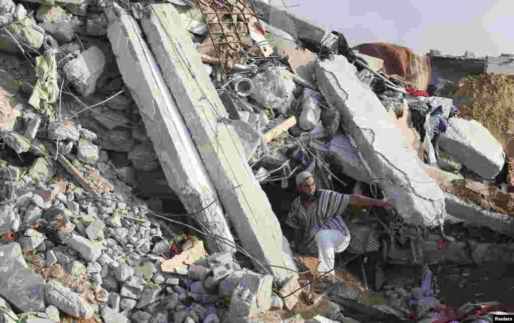 A Palestinian man searches for victims under the rubble of a house destroyed in an Israeli airstrike, in Rafah in the southern Gaza Strip, July 29, 2014.