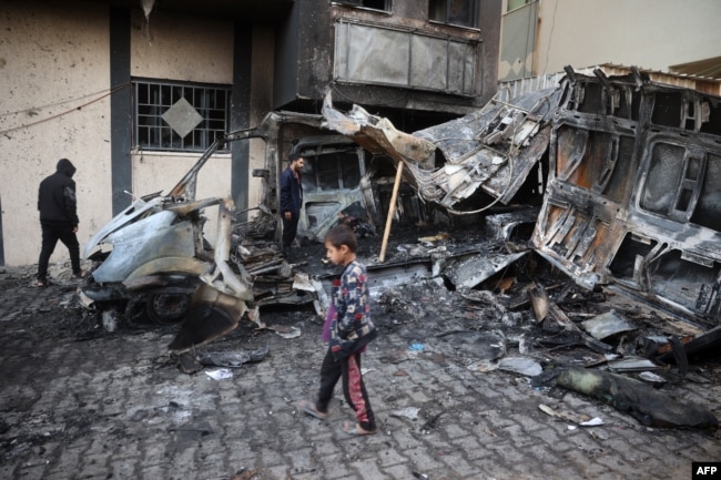 Seorang anak laki-laki berjalan melewati lokasi serangan Israel terhadap truk pengangkut, di kamp pengungsi Nuseirat di Jalur Gaza bagian tengah, pada tanggal 26 Desember 2024. (Foto: AFP)