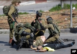 Binh sĩ Israel sơ cứu một đồng đội bị đâm bởi một người Palestine (mặc áo khoác màu vàng) trong cuộc đụng độ ở Bờ Tây, ngày 16/10/ 2015.