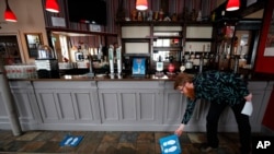 Owner Are Kjetil Kolltveit from Norway places markers for social distancing on the front of the bar at the Chandos Arms pub in London, July 1, 2020.
