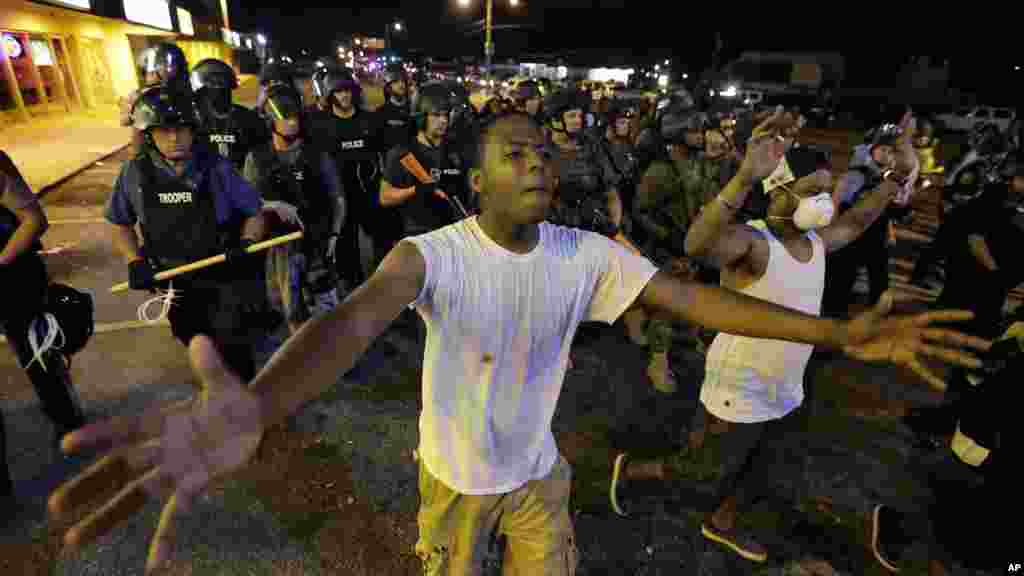 People are moved by a line of police as authorities disperse a protest in Ferguson, Missouri, early Aug. 20, 2014.