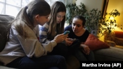 Kate McClintock, 12, left, Kate Green, 13, and Lilly Bond, 13, look at their smartphones at Lilly's home in Evanston, Ill. on Thursday, April 3, 2014. The friends are seventh-graders at Haven Middle School in Evanston, which was at the center of a controversy over its dress code. 