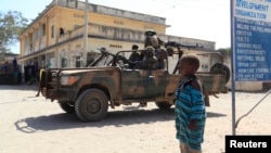 FILE - A boy looks on as Kenya Defense Force (KDF) soldiers, serving in the African Union Mission in Somalia (AMISOM), patrol the streets of Somalia's Kismayo town in lower Juba region, February 26, 2013. 
