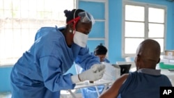 一名世卫组织人员在刚果姆班达卡为民众注射疫苗