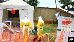 FILE - In this Sunday, Sept 9, 2018 file photo, health workers walk with a boy suspected of having the Ebola virus at an Ebola treatment center in Beni, Eastern Congo. 