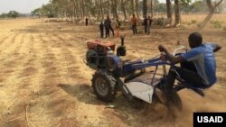 Mathew, a field engineer, stress tests the Smart Tractor at a test farm in Kaduna as kids from a nearby village watch. / Jehiel Oliver