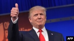 Donald Trump saat Real estate tycoon Donald Trump flashes the thumbs-up as he arrives on stage for the start of the prime time Republican presidential debate on Aug. 6, 2015 at the Quicken Loans Arena in Cleveland, Ohio.