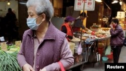 台灣一名婦人帶上口罩在一個露天菜市場走過。