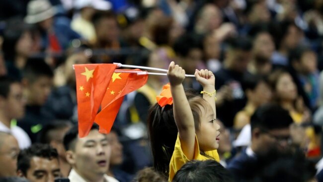 一个小女孩在上海举着两面中国国旗观看布鲁克林篮网队和洛杉矶湖人队的篮球比赛。（2019年10月10日）