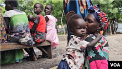 A mother and her child sit patiently, waiting for their turn to receive ready-to-eat therapeutic food at Koat Nutrition Center in Akobo East, South Sudan. (Sheila Ponnie/VOA)