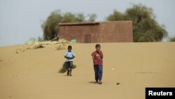 Boys walk on desert sands in the town of Moghtar-Lajjar in west Africa's Sahel region, where the United Nations says civil unrest and a drought have put 18 million people in food insecurity, May 25 2012.
