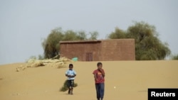 FILE - Boys walk on desert sands in the town of Moghtar-Lajjar in west Africa's Sahel region, where the United Nations says civil unrest and a drought have put 18 million people in food insecurity, May 25 2012.