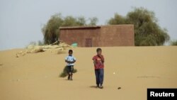 FILE - Boys walk on desert sands in the town of Moghtar-Lajjar in west Africa's Sahel region, where the U.N. says civil unrest and drought conditions have put tens of millions of people at risk of food insecurity.