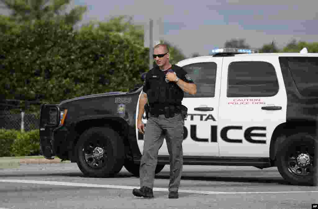 A Marietta police officer stops traffic during the morning commute on the busy U.S. Highway 41 while a motorcade transporting an American infected with the deadly Ebola virus from West Africa leaves Dobbins Air Reserve Base, Marietta, Georgia, Sept. 9, 2014.